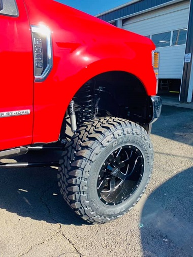 Close up of suspension lift kit installed on red Ford truck